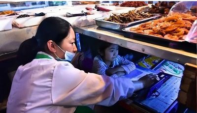 Gadis Kecil Asal Tiongkok Ini Fokus Belajar Online di Bawah Gerobak Dagangan Orang Tuanya
