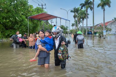 Warga menggendong anaknya saat melintasi jalan yang terendam banjir di Perumahan Duta Bandara Permai, Kosambi, Kabupaten Tangerang, Banten, Senin (12 1 2026). - Foto oleh ANTARA FOTO Putra M. Akbar