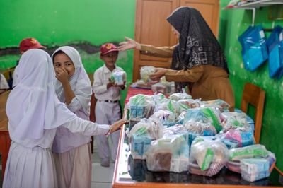 Guru membagikan menu Makan Bergizi Gratis (MBG) kepada siswa di SD Negeri 1 Bojongleles, Lebak, Banten, Senin (23 2 2026). - Foto oleh ANTARA FOTO Muhammad Bagus Khoirunas