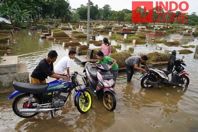 FOTO: Banjir di TPU Tanah Kusir Dimanfaatkan Warga untuk Cuci Motor
