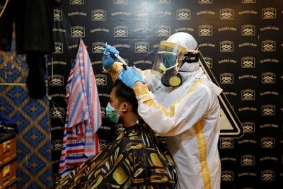 FOTO: Cegah Virus Corona, Tukang Cukur Ini Pakai Baju APD Buatan Sendiri