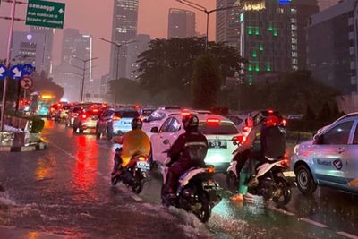 Potret Pemotor Berjuang Lintasi Sudirman Macet di Tengah Hujan Lebat dan Langit Jingga