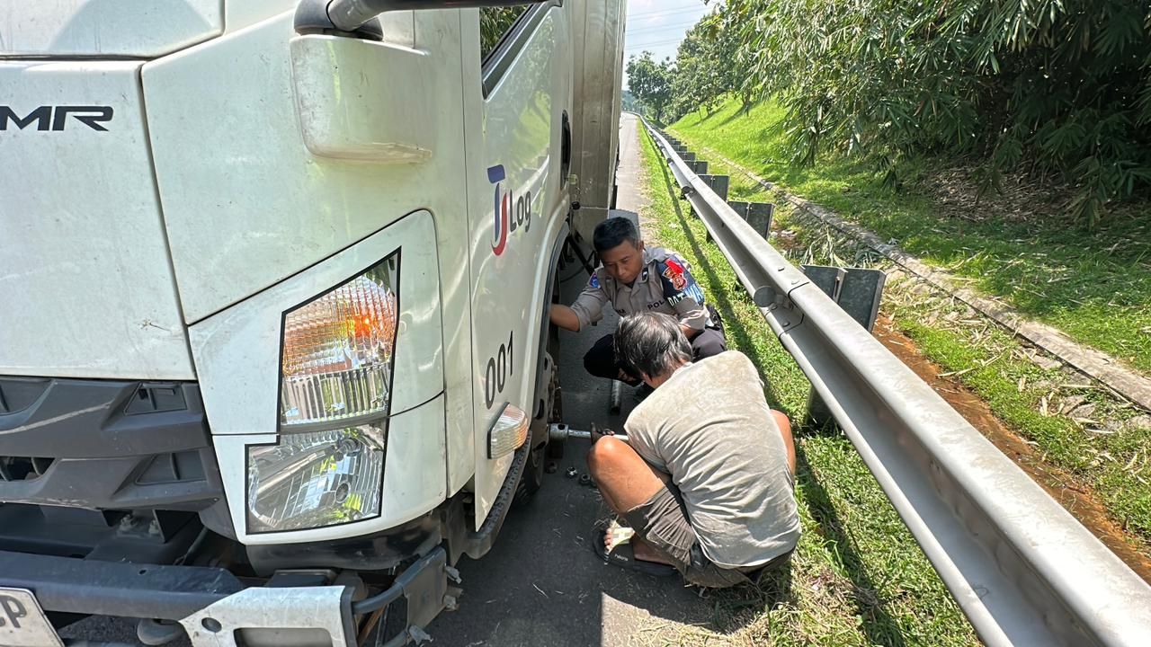 Personel Satlantas Polres Purwakarta Bantu Kendaraan Logistik Pecah Ban di KM 80.200